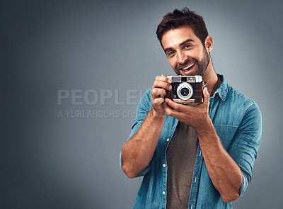 Buy stock photo Studio shot of a handsome young man using a camera against a grey background