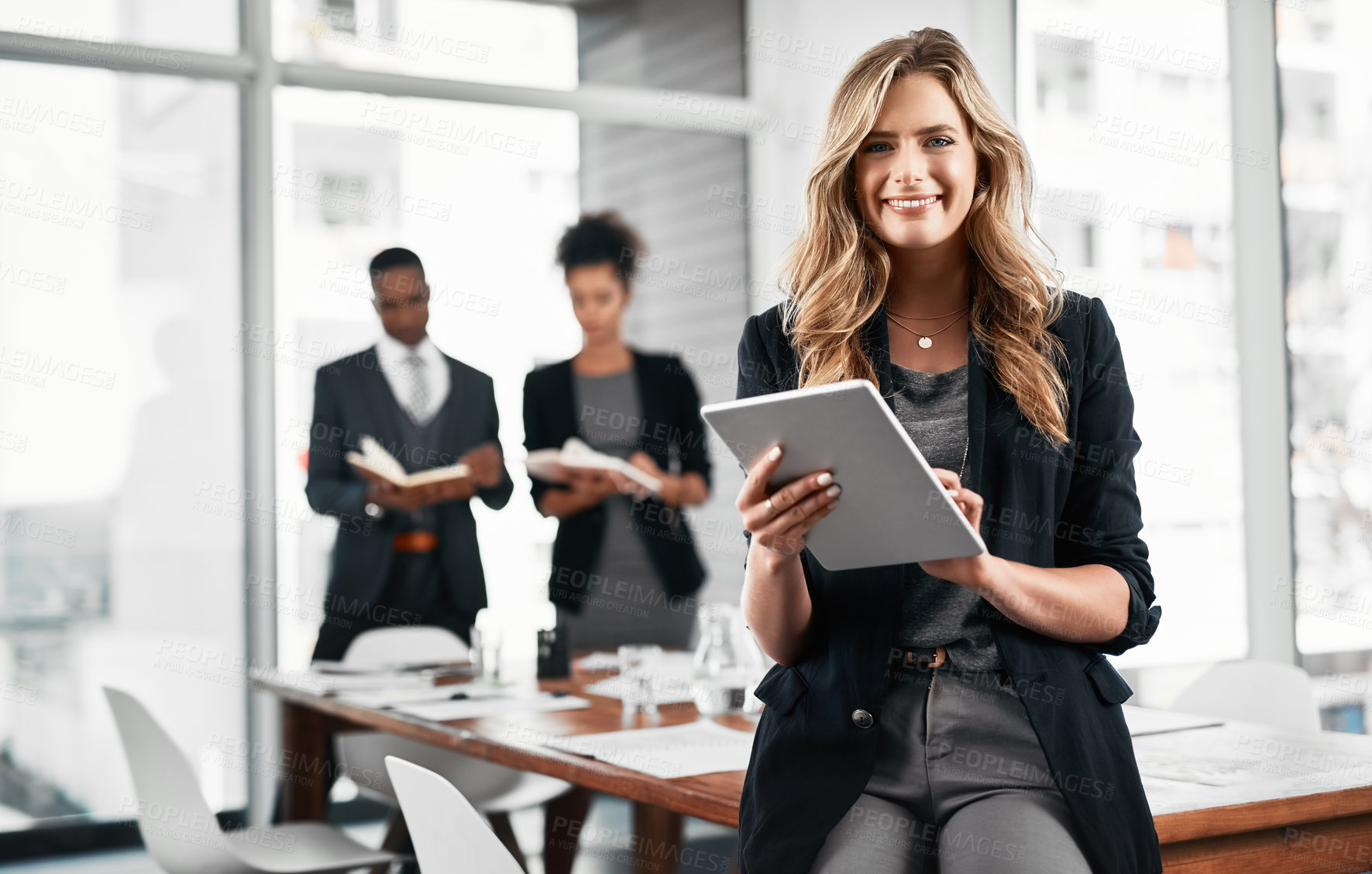 Buy stock photo Portrait of a young businesswoman using a digital tablet in an office with her colleagues in the background