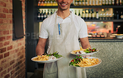 Buy stock photo Shot of an unrecognizable waiter holding three plates of food that he's going to serve to customers inside of a restaurant during the day