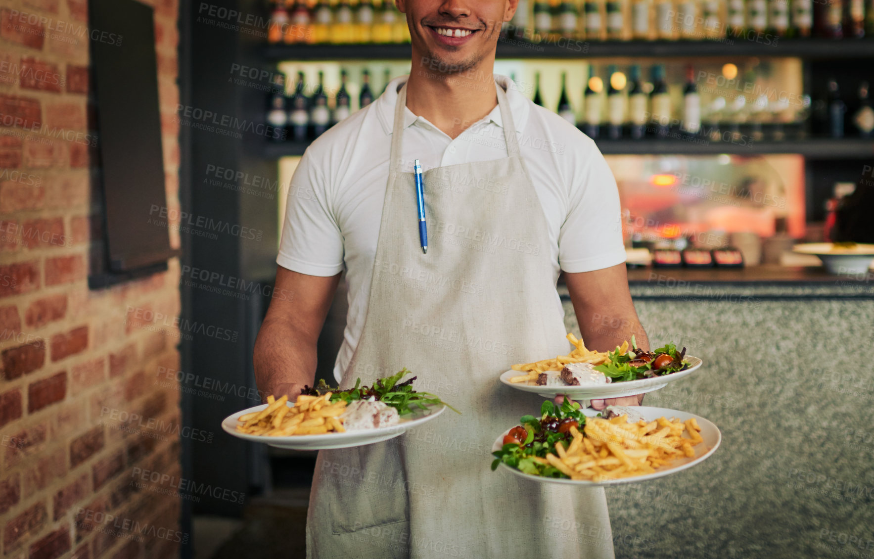 Buy stock photo Shot of an unrecognizable waiter holding three plates of food that he's going to serve to customers inside of a restaurant during the day