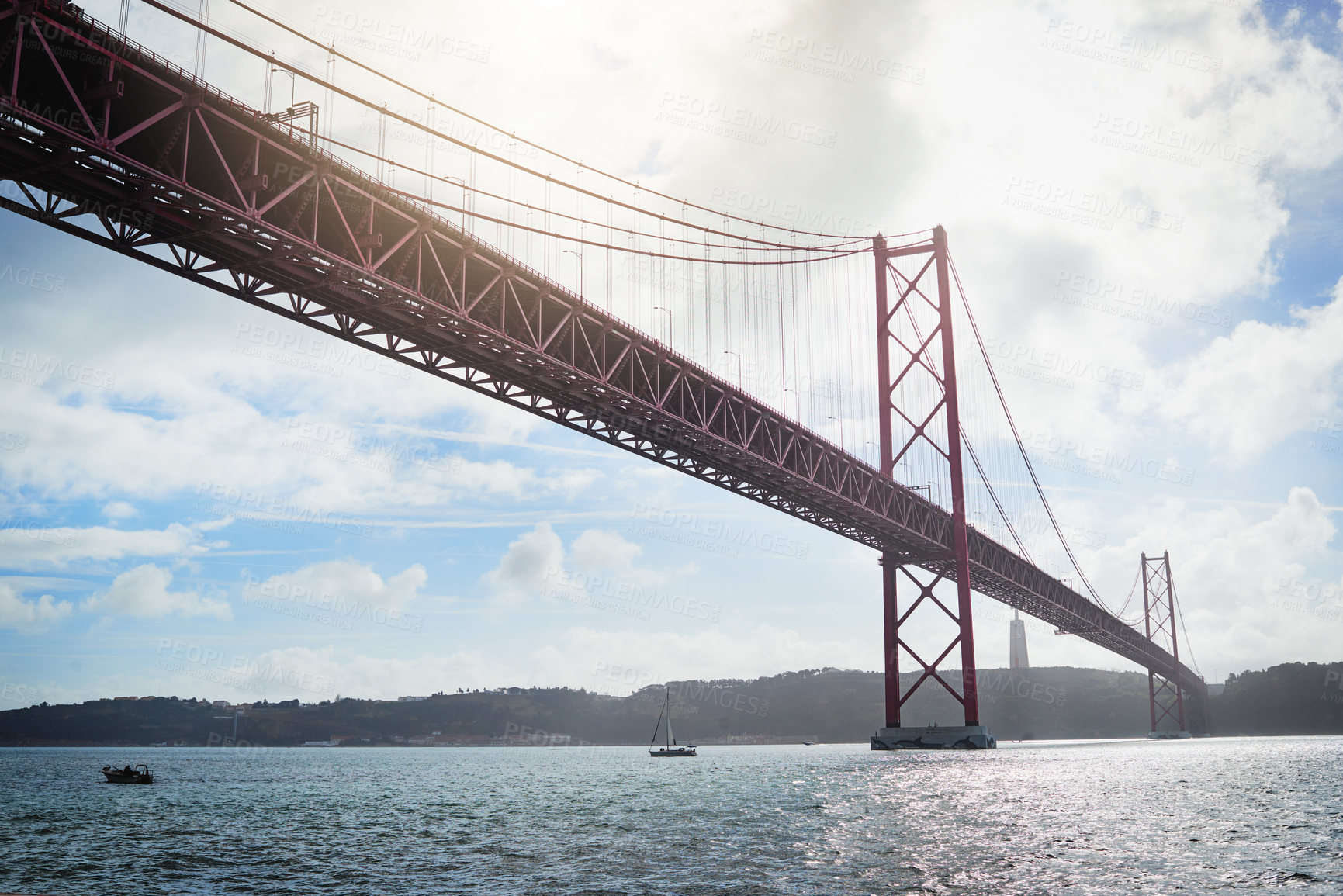 Buy stock photo Low angle shot of a massive bridge over the ocean with clouds in the background outside during the day