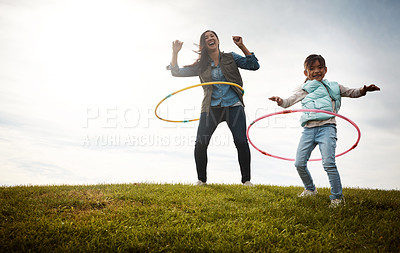 Buy stock photo Shot of a little girl and her mom having a hula hoop challenge