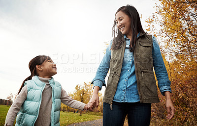 Buy stock photo Happy mom, walking and holding hands with child for bonding, outdoor adventure or journey in nature. Mother strolling with daughter, kid or little girl on sidewalk in autumn season at park together