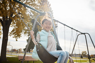 Buy stock photo Portrait of an adorable little girl playing on a swing at the park