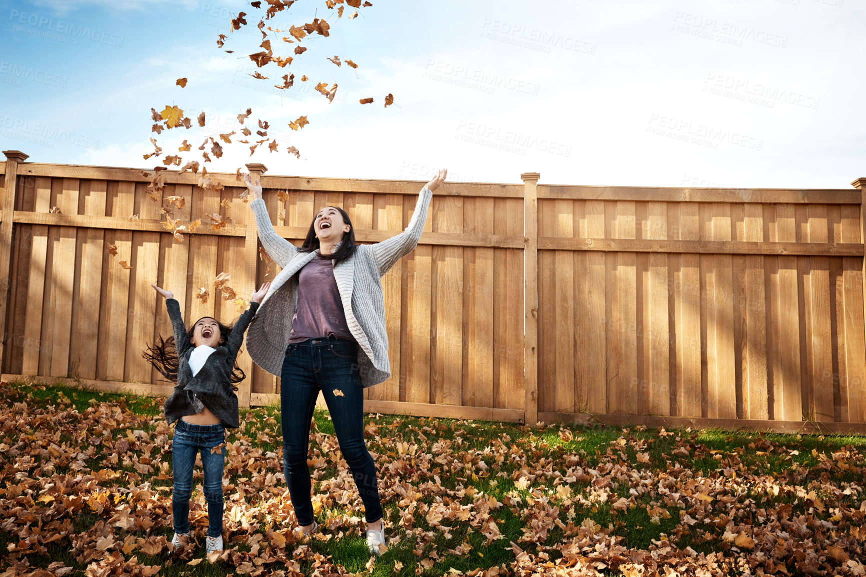 Buy stock photo Leaf, mother and daughter in autumn to throw together at backyard of home for bonding or love. Asian family, energy or fall with single parent woman and girl child having fun in backyard for wellness