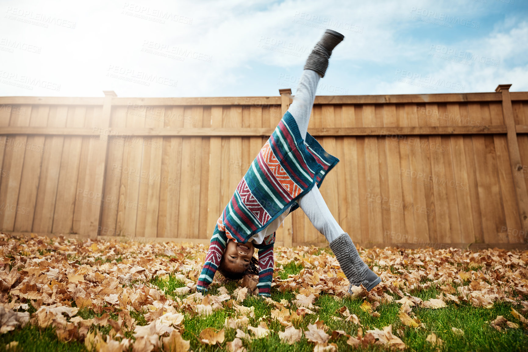 Buy stock photo Shot of an adorable little girl doing cartwheels an autumn day outdoors