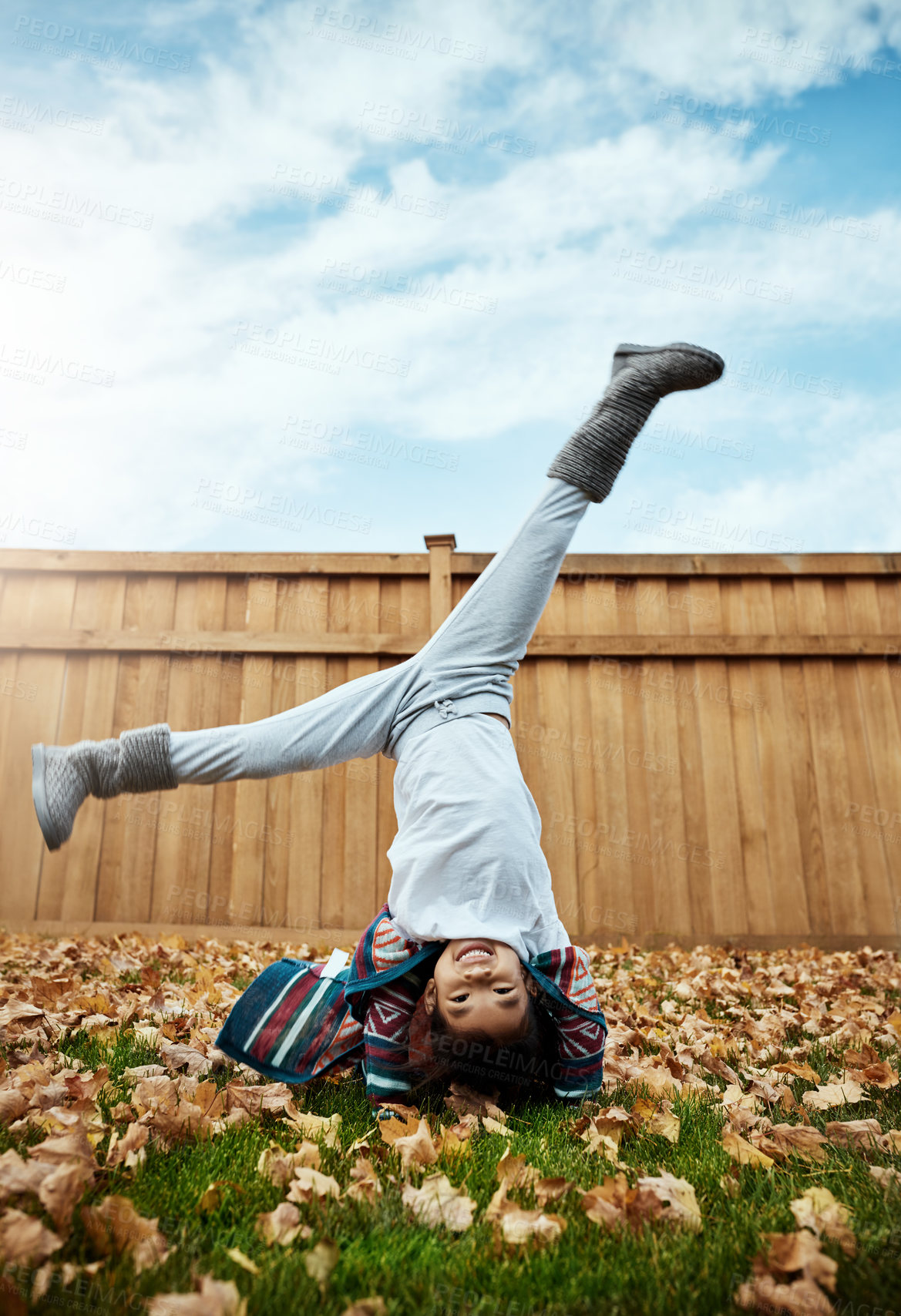 Buy stock photo Shot of an adorable little girl doing cartwheels an autumn day outdoors