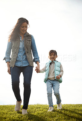 Buy stock photo Shot of a woman holding her little girl's hand as they walk outdoors