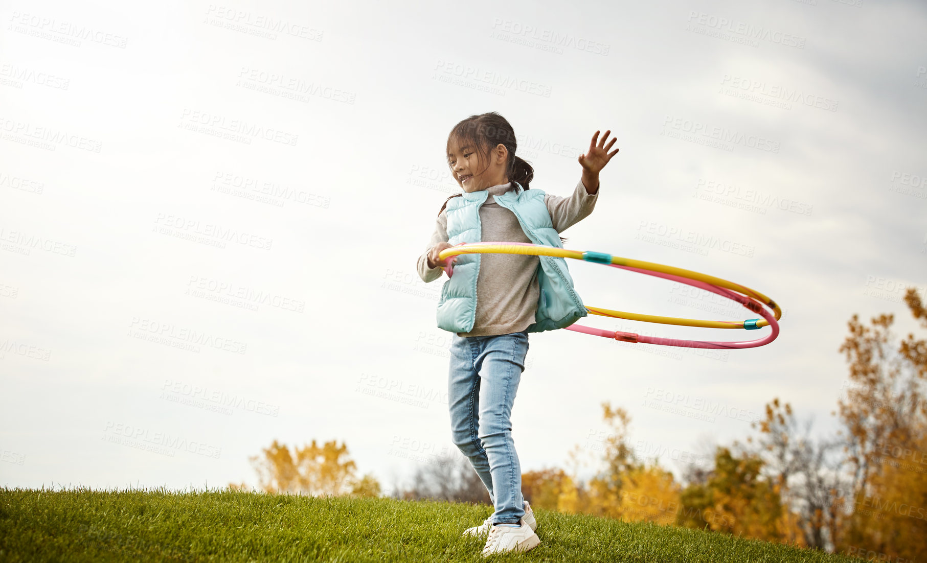 Buy stock photo Girl, dance and hoop in field, fun and plastic ring for practice in nature on holiday outing. Alone, toys and vacation in autumn with trees for young child person, clouds and grass for play exercise