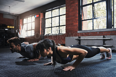 Buy stock photo Shot of two young people working out at the gym