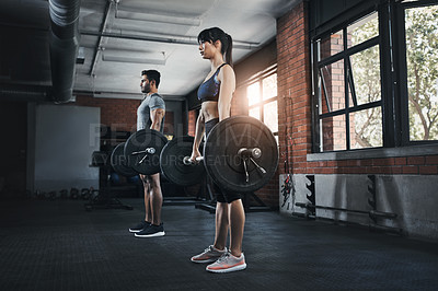 Buy stock photo Shot of a young man and woman working out with weights at the gym