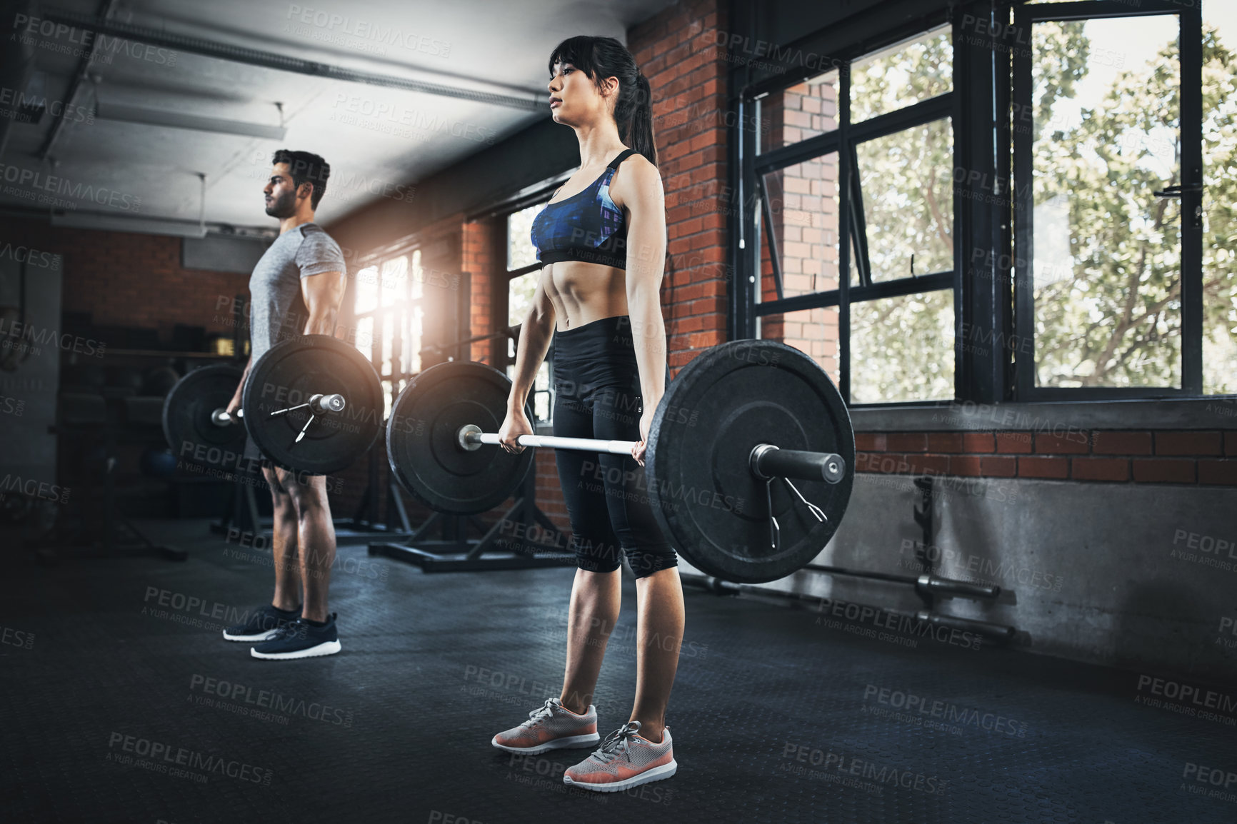Buy stock photo Shot of a young man and woman working out with weights at the gym