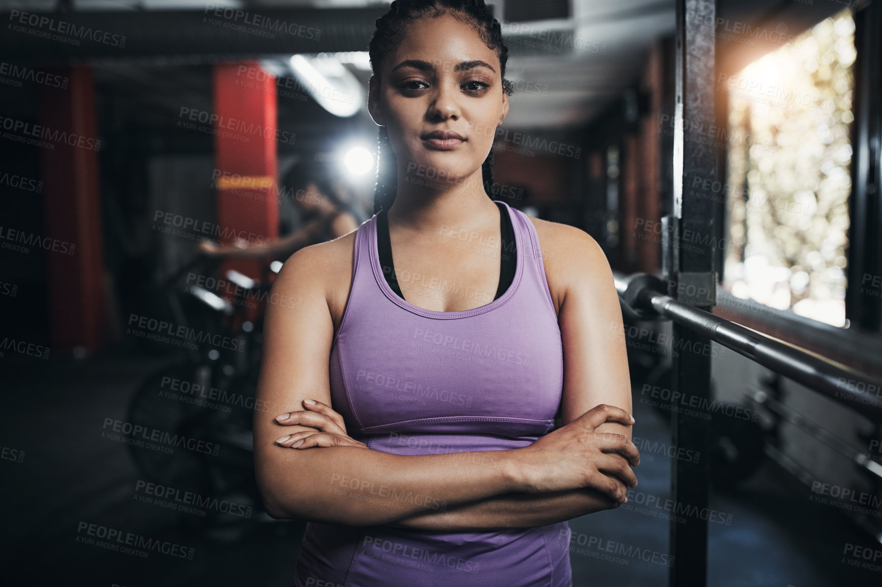 Buy stock photo Shot of a sporty young woman standing with her arms crossed in the gym