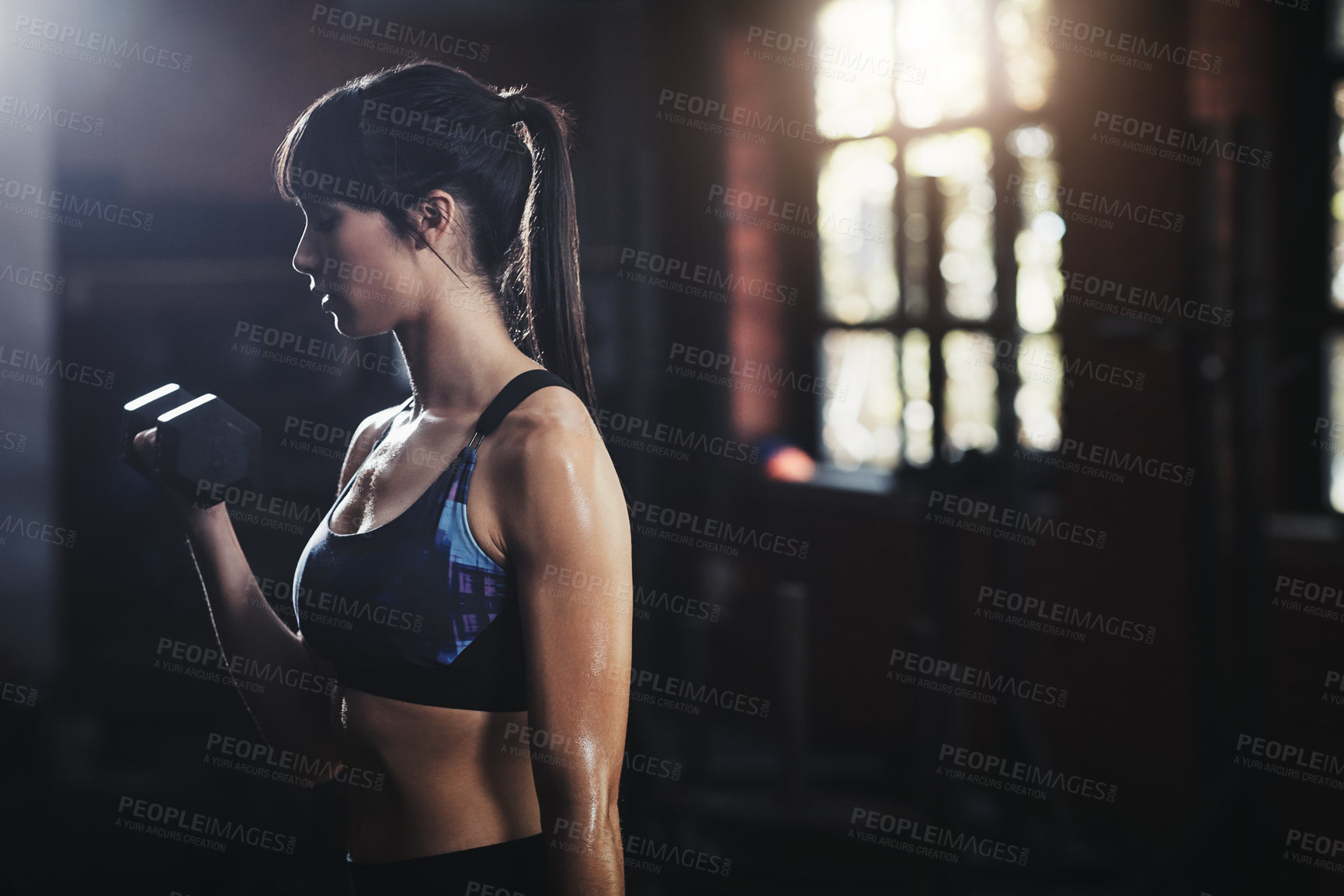 Buy stock photo Cropped shot of a beautiful young woman lifting dumbbells at the gym