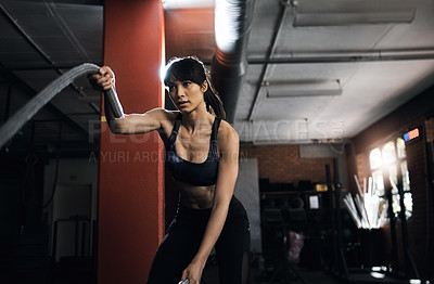 Buy stock photo Shot of a young woman doing heavy rope training at the gym