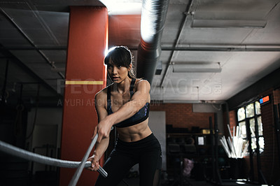 Buy stock photo Shot of a young woman doing heavy rope training at the gym