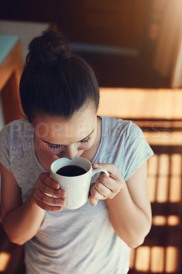 Buy stock photo Shot of an attractive young woman enjoying her morning coffee while standing in the kitchen at home