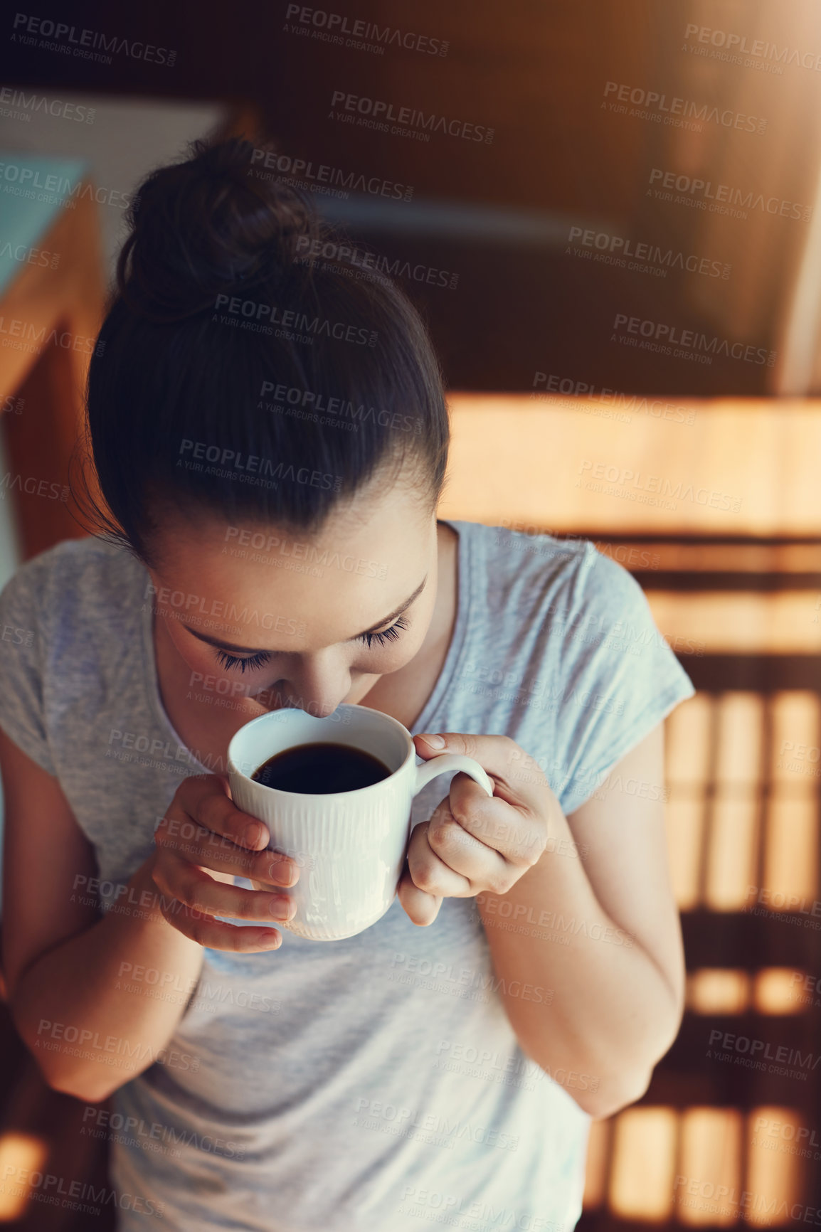 Buy stock photo Shot of an attractive young woman enjoying her morning coffee while standing in the kitchen at home