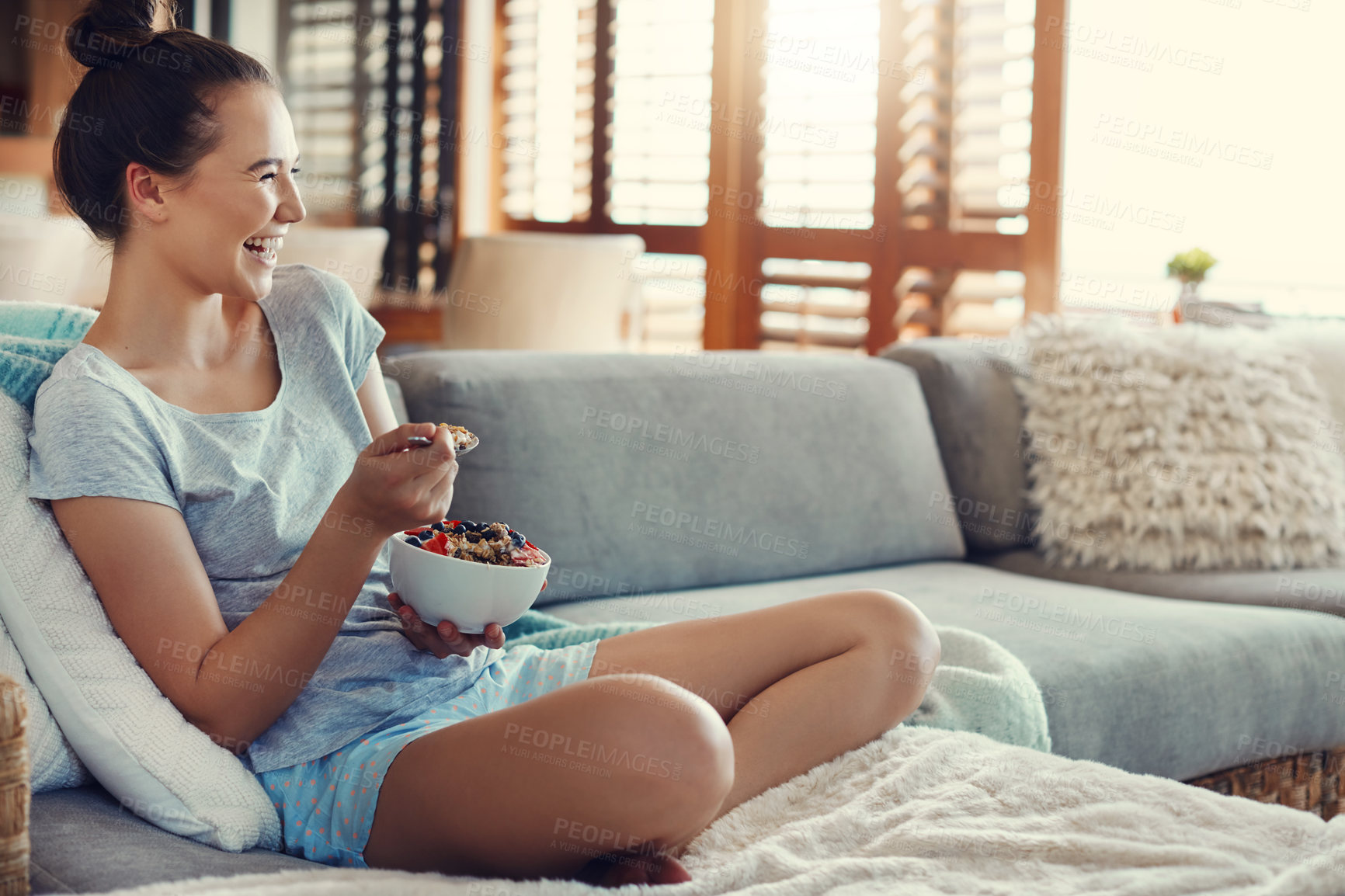 Buy stock photo Sofa, woman and laughing with bowl of fruit at home for breakfast or healthy meal. House, morning and happy with organic snack for nutrition, diet and food for wellness and self care in living room