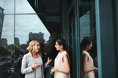 Buy stock photo Shot of two businesswomen having a discussion on the office balcony