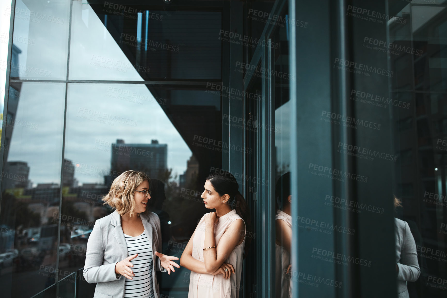 Buy stock photo Shot of two businesswomen having a discussion on the office balcony