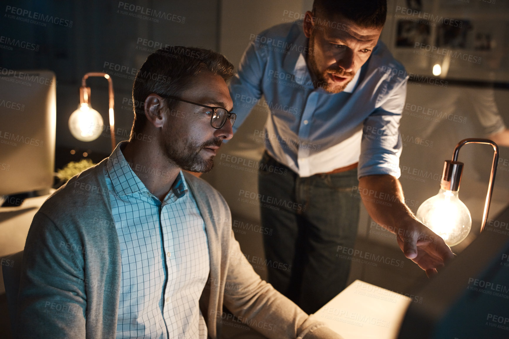 Buy stock photo Shot of two businesspeople working late on a computer in an office
