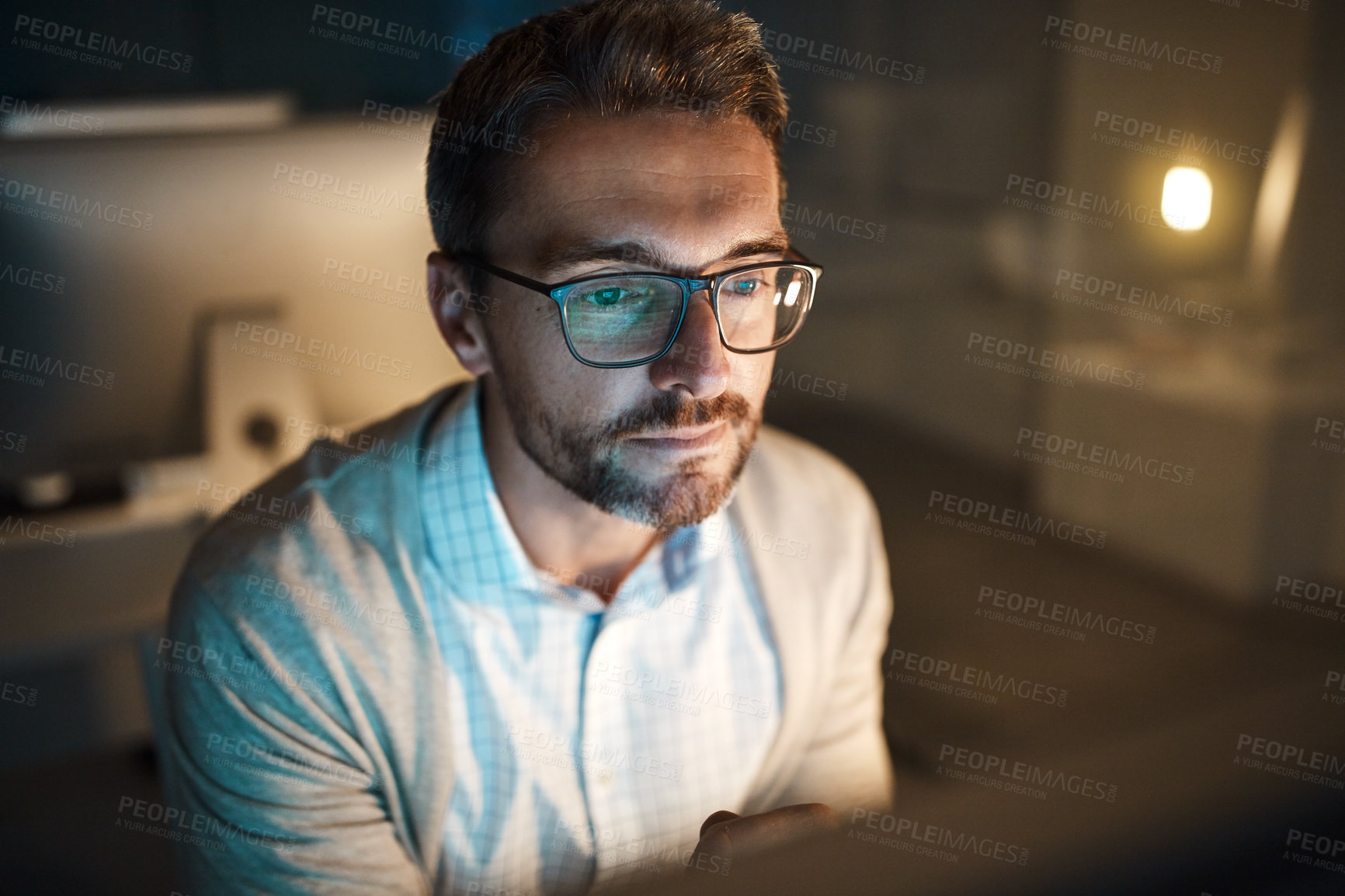 Buy stock photo Shot of a mature businessman working late on a computer in an office
