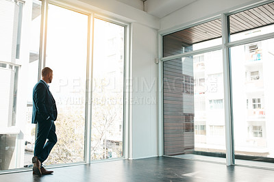 Buy stock photo Shot of a mature businessman looking out the window in an office