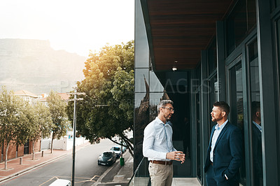 Buy stock photo Shot of two businessmen having a discussion on the office balcony