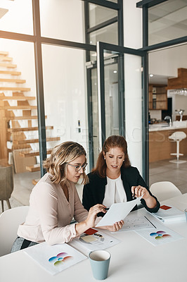 Buy stock photo Shot of two businesswomen going through paperwork together in an office