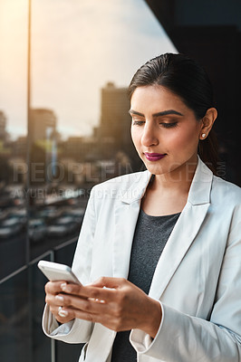 Buy stock photo Shot of a young businesswoman using her cellphone on the office balcony