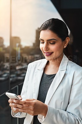 Buy stock photo Shot of a young businesswoman using her cellphone on the office balcony