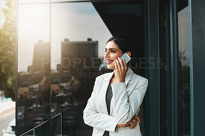 Buy stock photo Shot of a young businesswoman talking on a cellphone on the office balcony
