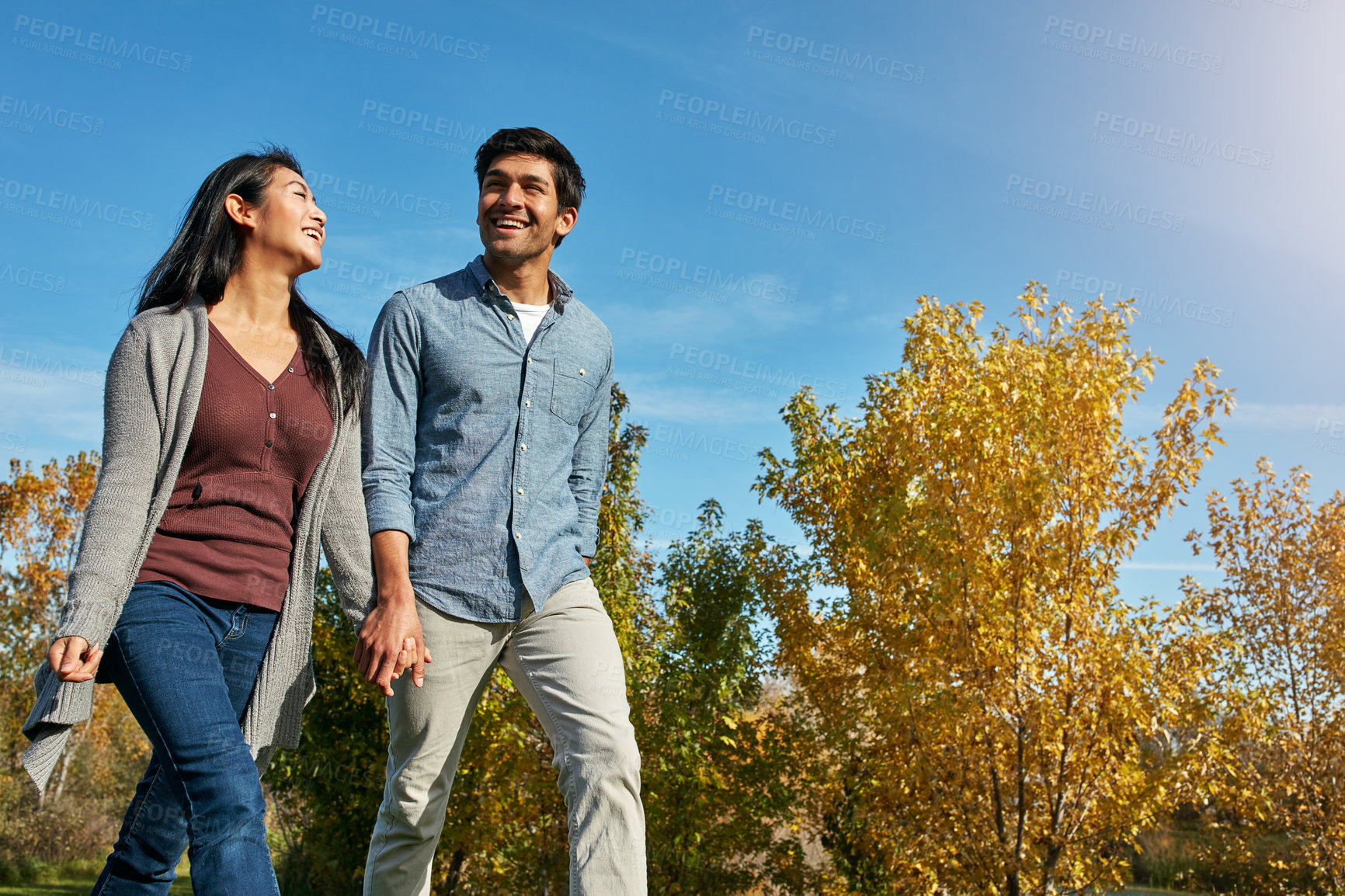 Buy stock photo Shot of a loving young couple out for a walk in the park