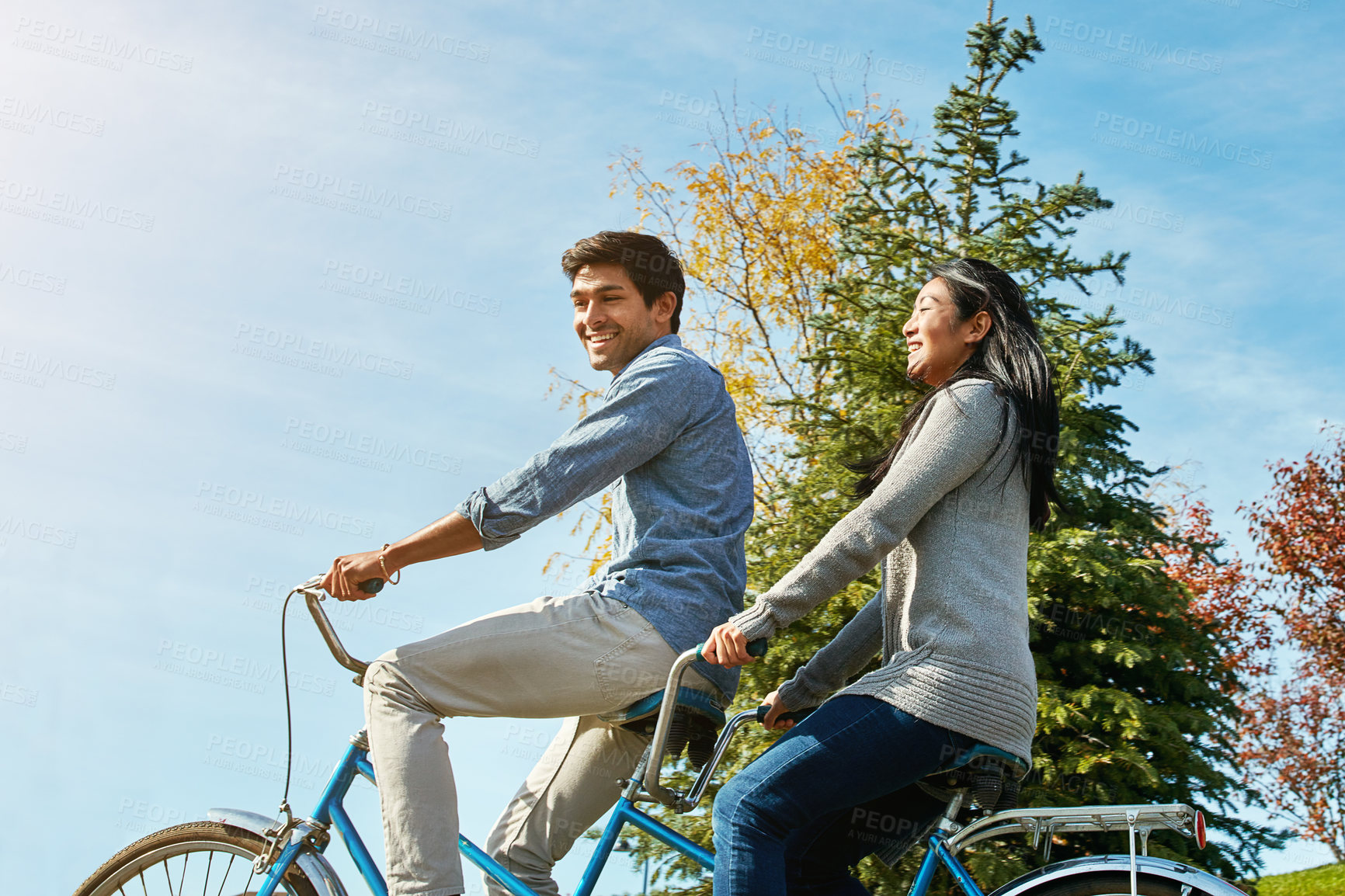 Buy stock photo Shot of a young couple out for a ride on a tandem bicycle