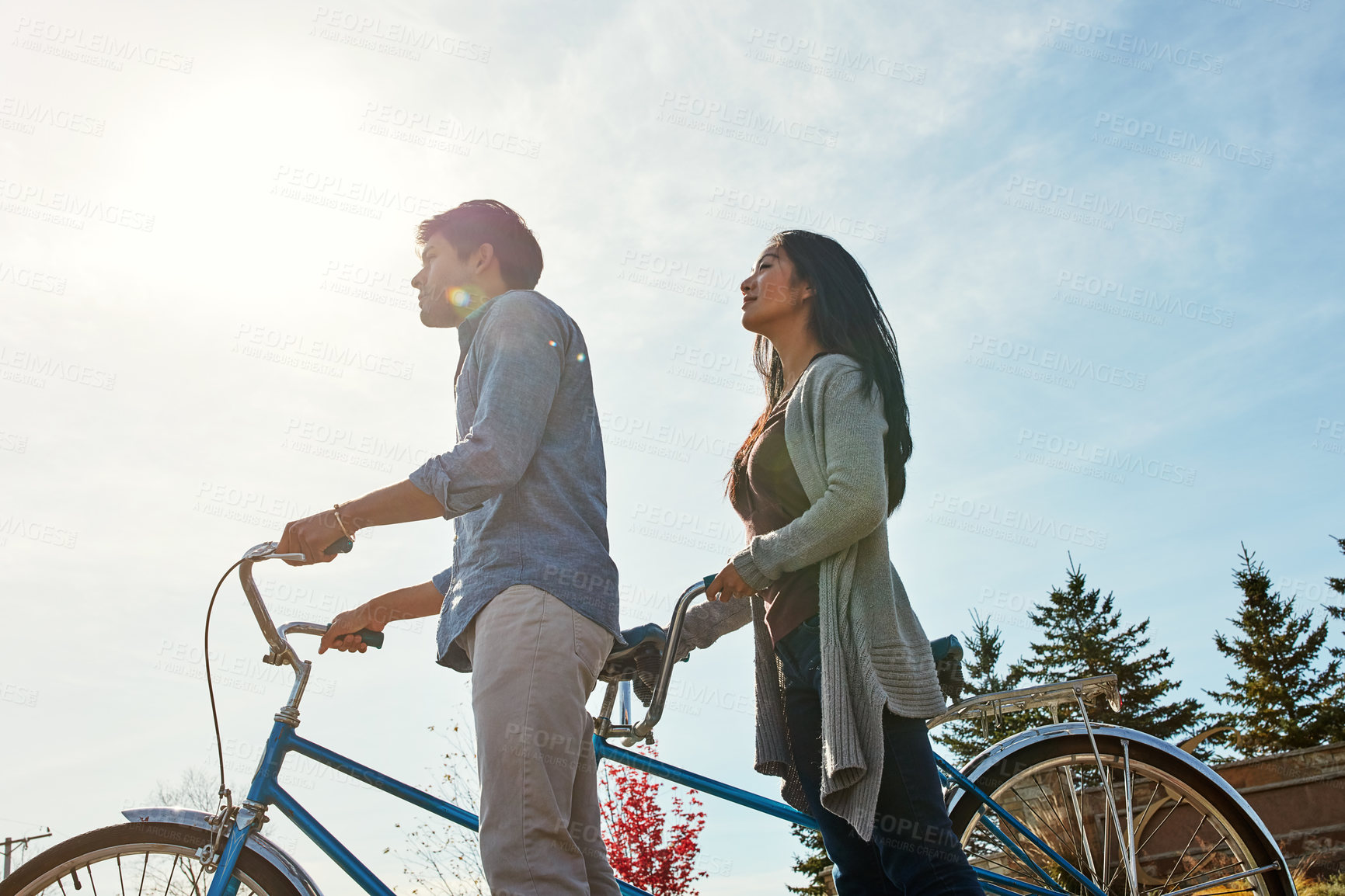 Buy stock photo Shot of a young couple out for a ride on a tandem bicycle