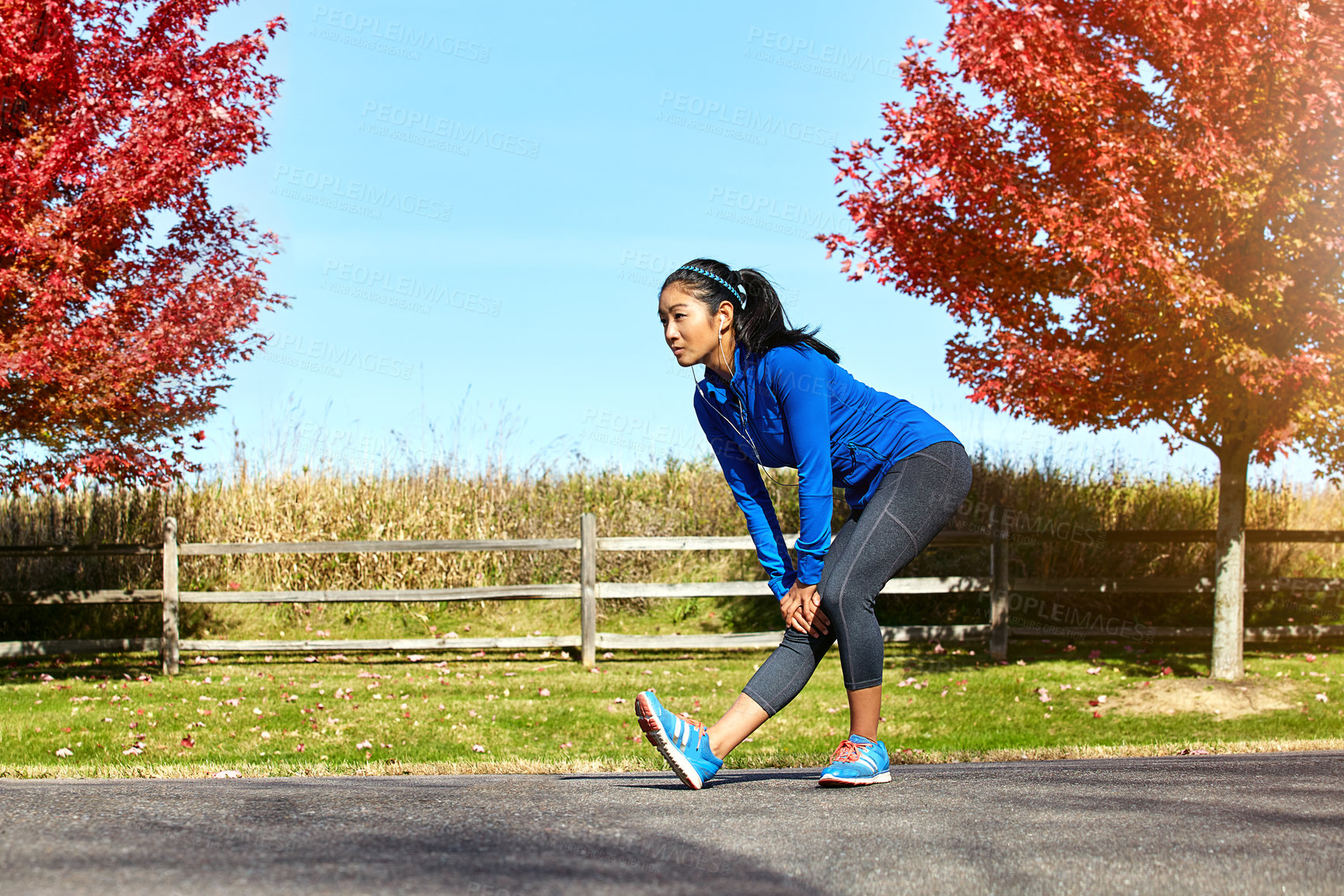 Buy stock photo Shot of a sporty young woman stretching her legs while exercising outdoors