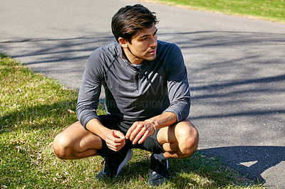 Buy stock photo Shot of a sporty young man taking a break while exercising outdoors