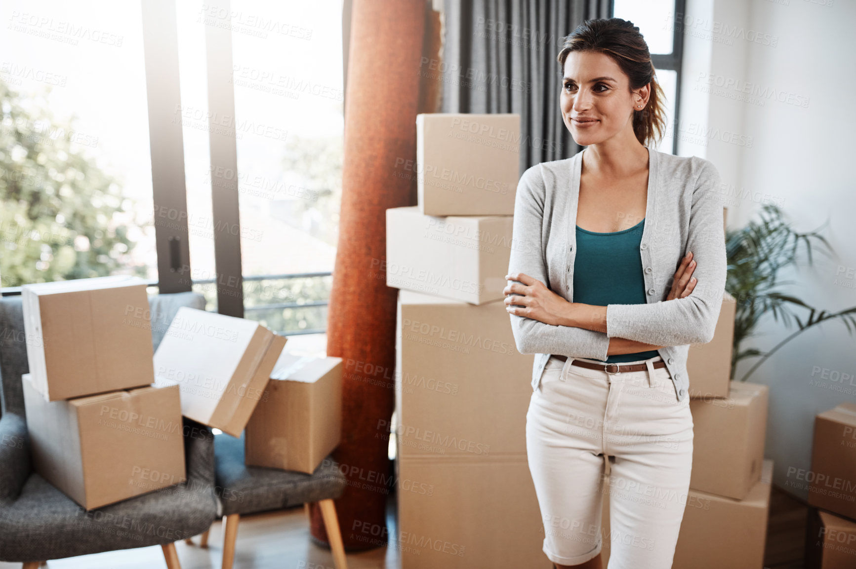 Buy stock photo Cropped shot of an attractive young woman standing with her arms folded while moving into a new house