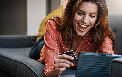 Buy stock photo Shot of an attractive young woman using a digital tablet and credit card on the sofa at home