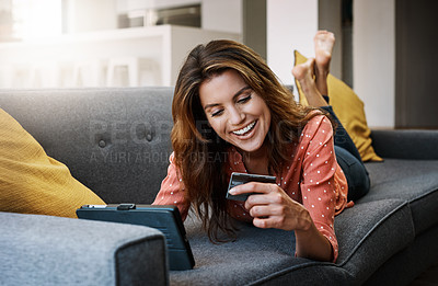 Buy stock photo Shot of an attractive young woman using a digital tablet and credit card on the sofa at home