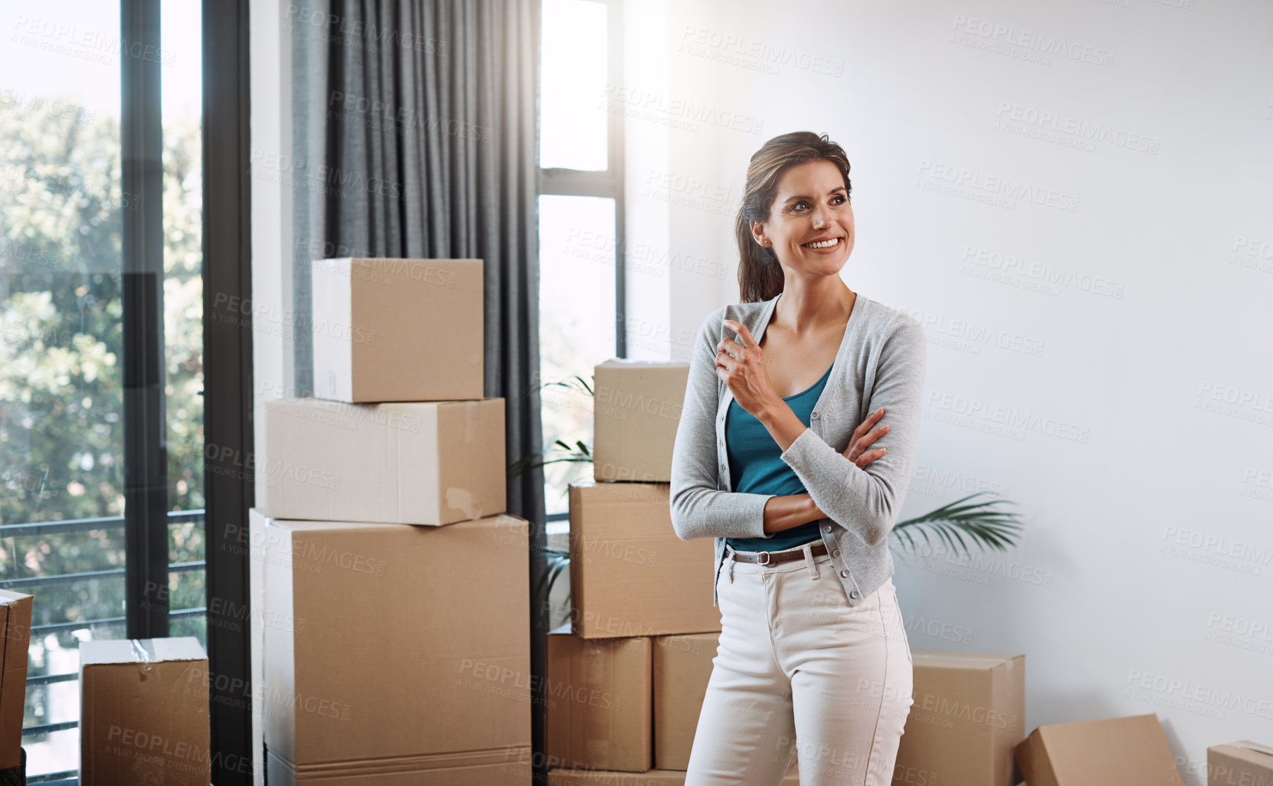 Buy stock photo Cropped shot of an attractive young woman looking thoughtful standing in her new home while moving in
