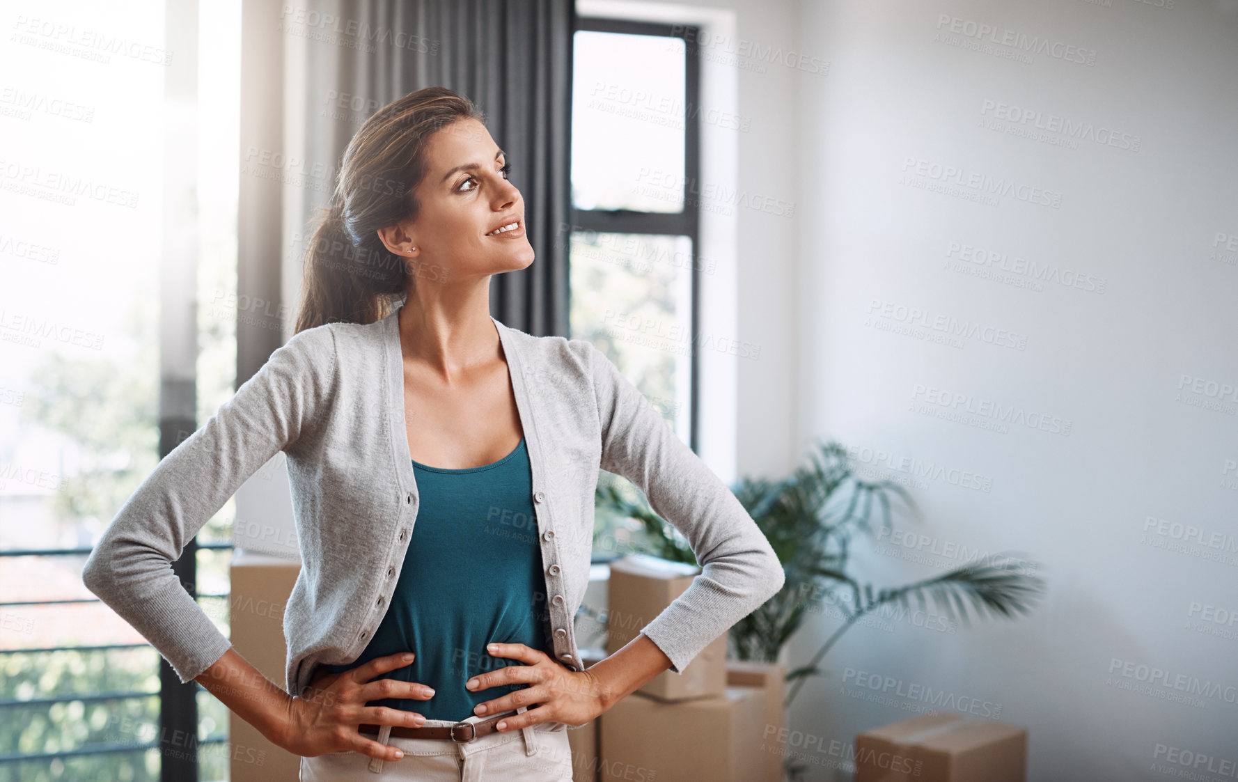 Buy stock photo Cropped shot of an attractive young woman standing with her hands on her hips while moving into a new house