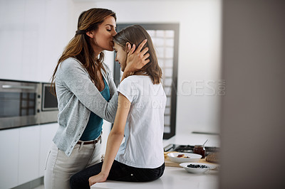 Buy stock photo Cropped shot of an attractive young woman kissing her daughter on the forehead while spending time together at home