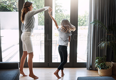 Buy stock photo Full length shot of an attractive young woman and her daughter dancing while spending time together at home
