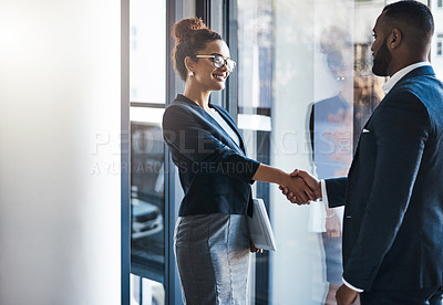 Buy stock photo Shot of two businesspeople shaking hands in an office