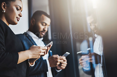 Buy stock photo Shot of two businesspeople using their cellphones in an office
