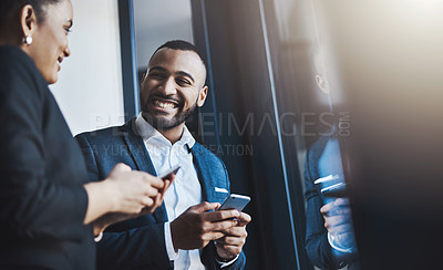 Buy stock photo Shot of two businesspeople using their cellphones in an office