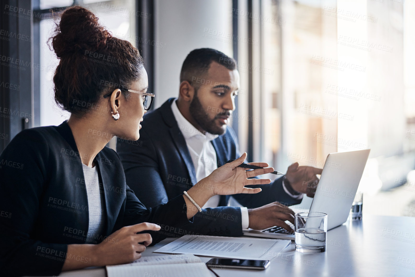 Buy stock photo Shot of two businesspeople working together on a laptop in an office