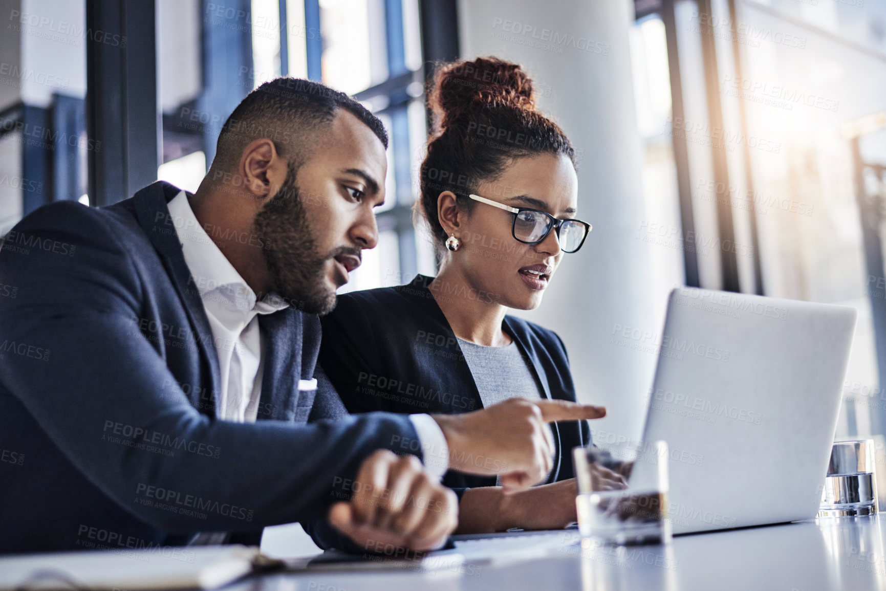 Buy stock photo Shot of two businesspeople working together on a laptop in an office